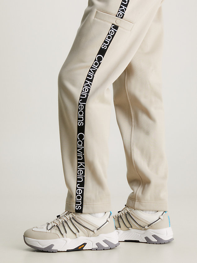 beige swobodne spodnie dresowe z taśmą z logo dla mężczyźni - calvin klein jeans